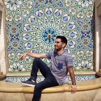 ashkon sitting in front of a blue mosaic
