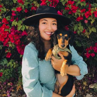 counselor Jacquie in a hat holding her dog